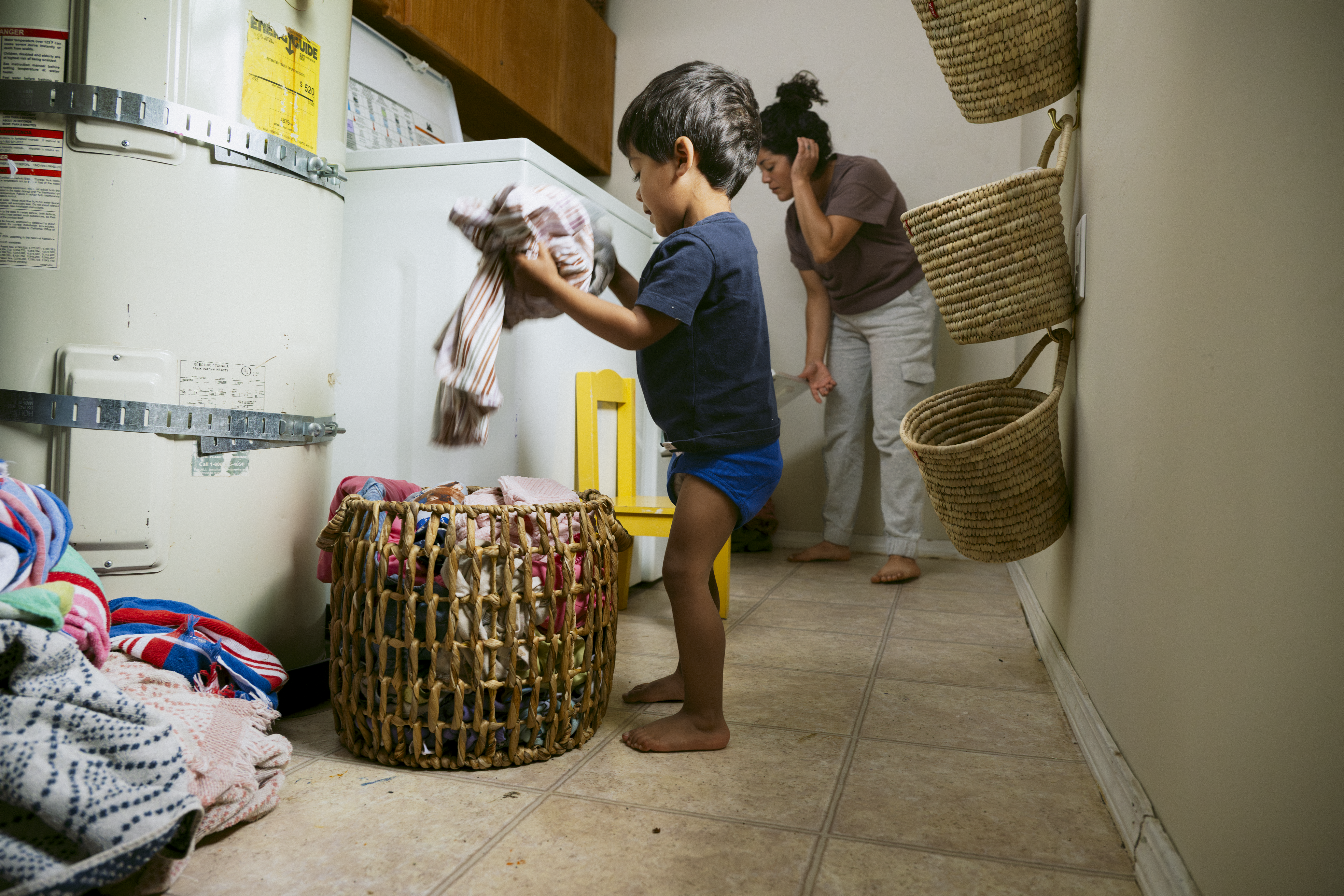 Boy and mom doing laundry in messy laundry room.